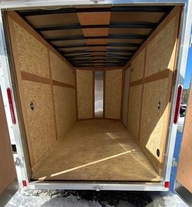 Empty enclosed trailer with wooden interior walls and floor.