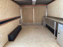 Empty cargo trailer with plywood walls and metal storage cabinets.