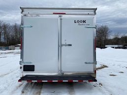 Rear view of a white enclosed trailer on snowy ground.