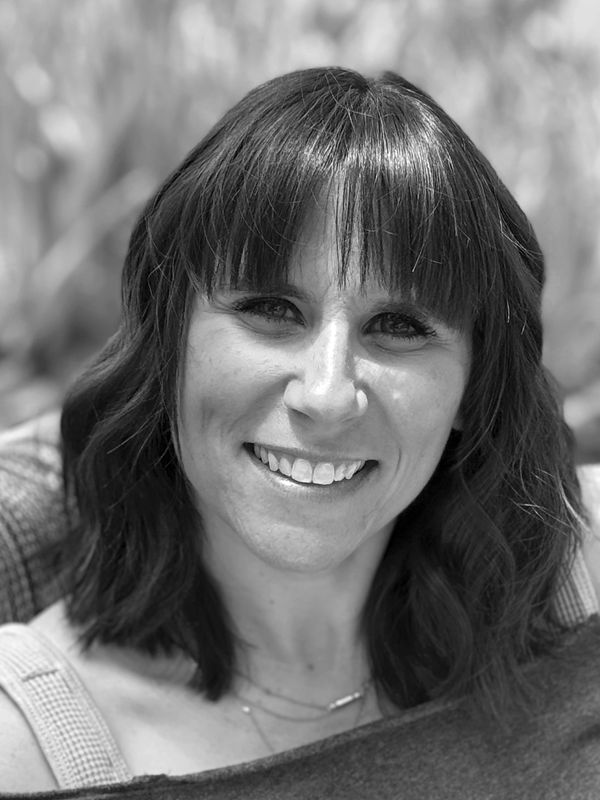 Close-up portrait of a smiling woman with dark hair and bangs.