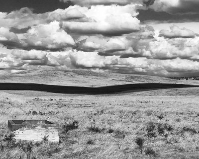 Black and white landscape with rolling hills and dramatic clouds.