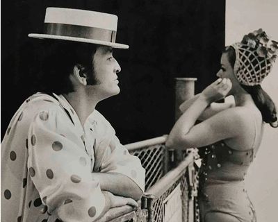 Man in polka dot shirt and hat, woman in vintage swimwear.