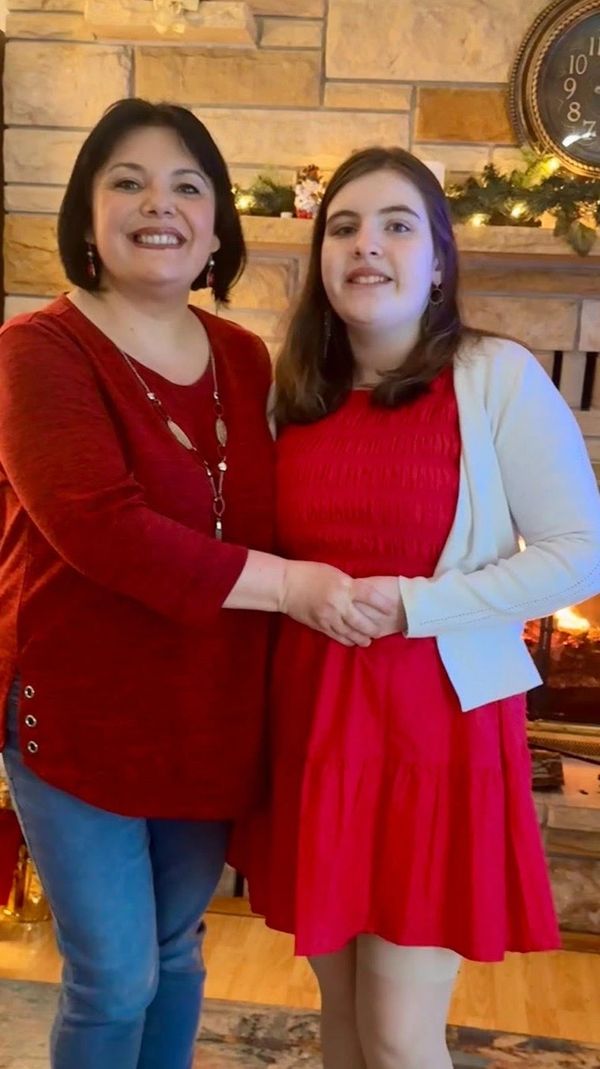 Two women smiling and holding hands in a cozy living room with festive decorations.