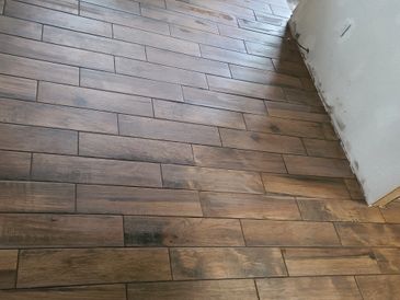 Brown wood-patterned floor tiles in a room under construction.