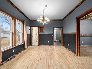 Empty room with wooden floor, blue and black walls, and large windows.