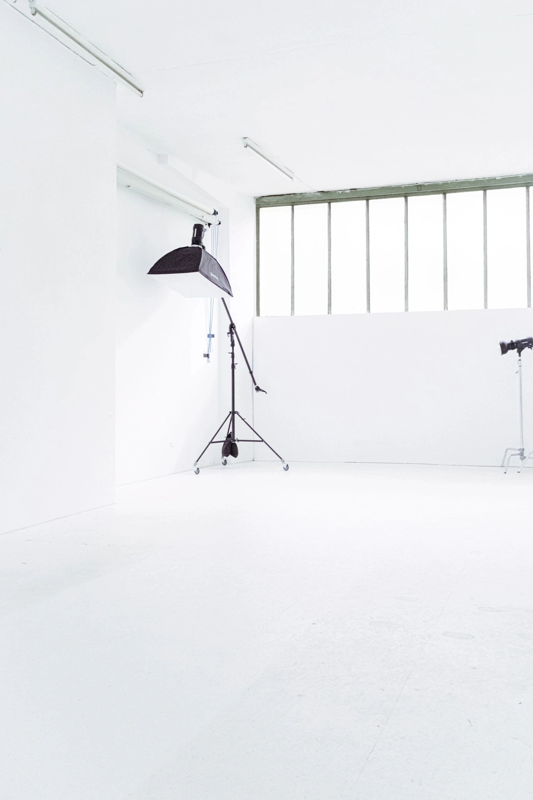 Minimalistic photography studio with white walls and lighting equipment.