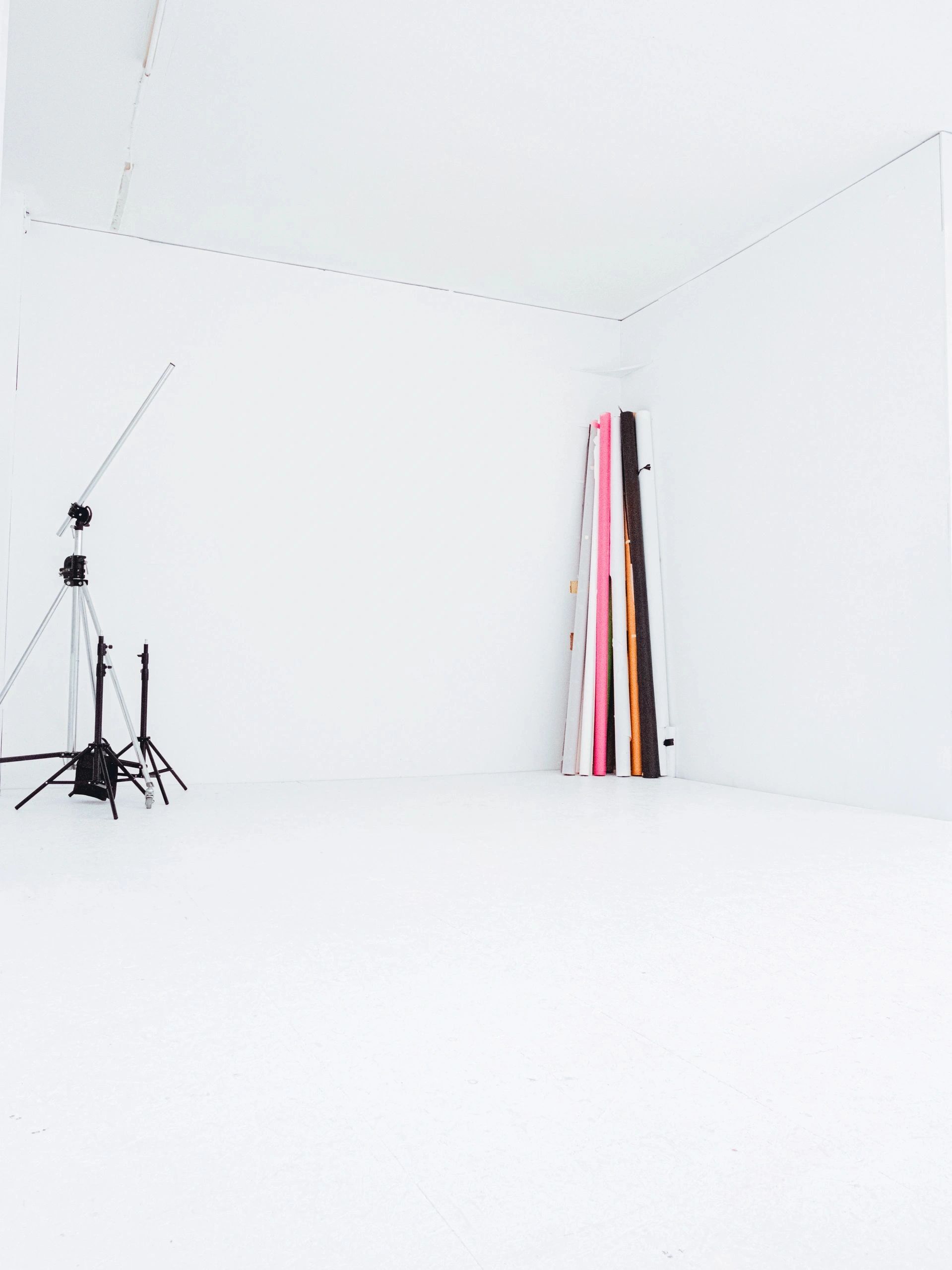 Minimalist photography studio with white walls and rolled backdrops.