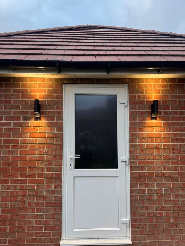 White door on a brick house with wall lights.