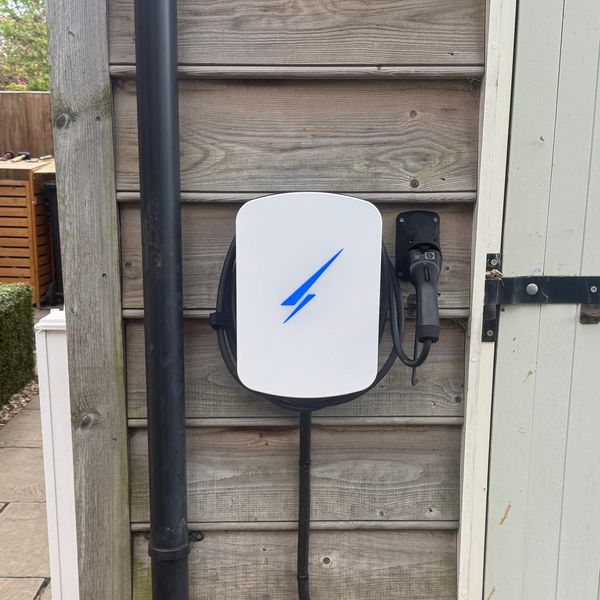 Electric vehicle charging station mounted on a wooden wall.