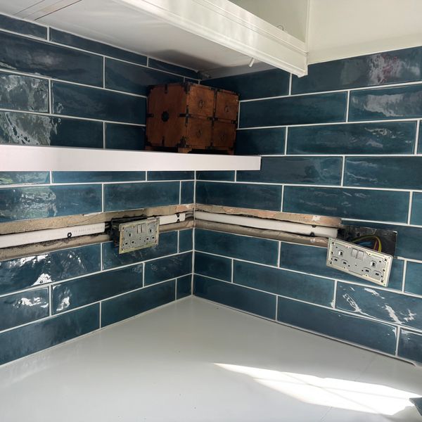 Kitchen backsplash with blue tiles and exposed wiring.