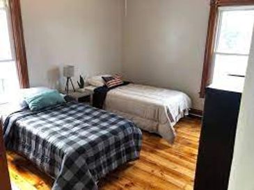 Cozy bedroom with two single beds and wooden flooring.
