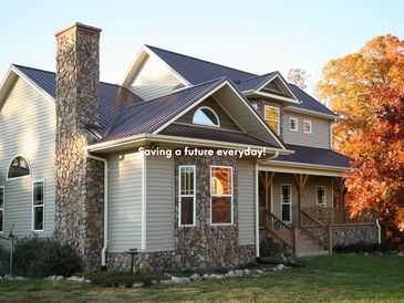 Spacious house with stone chimney and autumn trees.