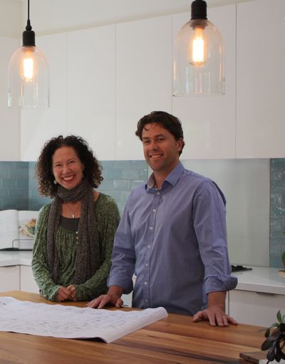 Smiling man and woman in a modern kitchen with blue tile backsplash.