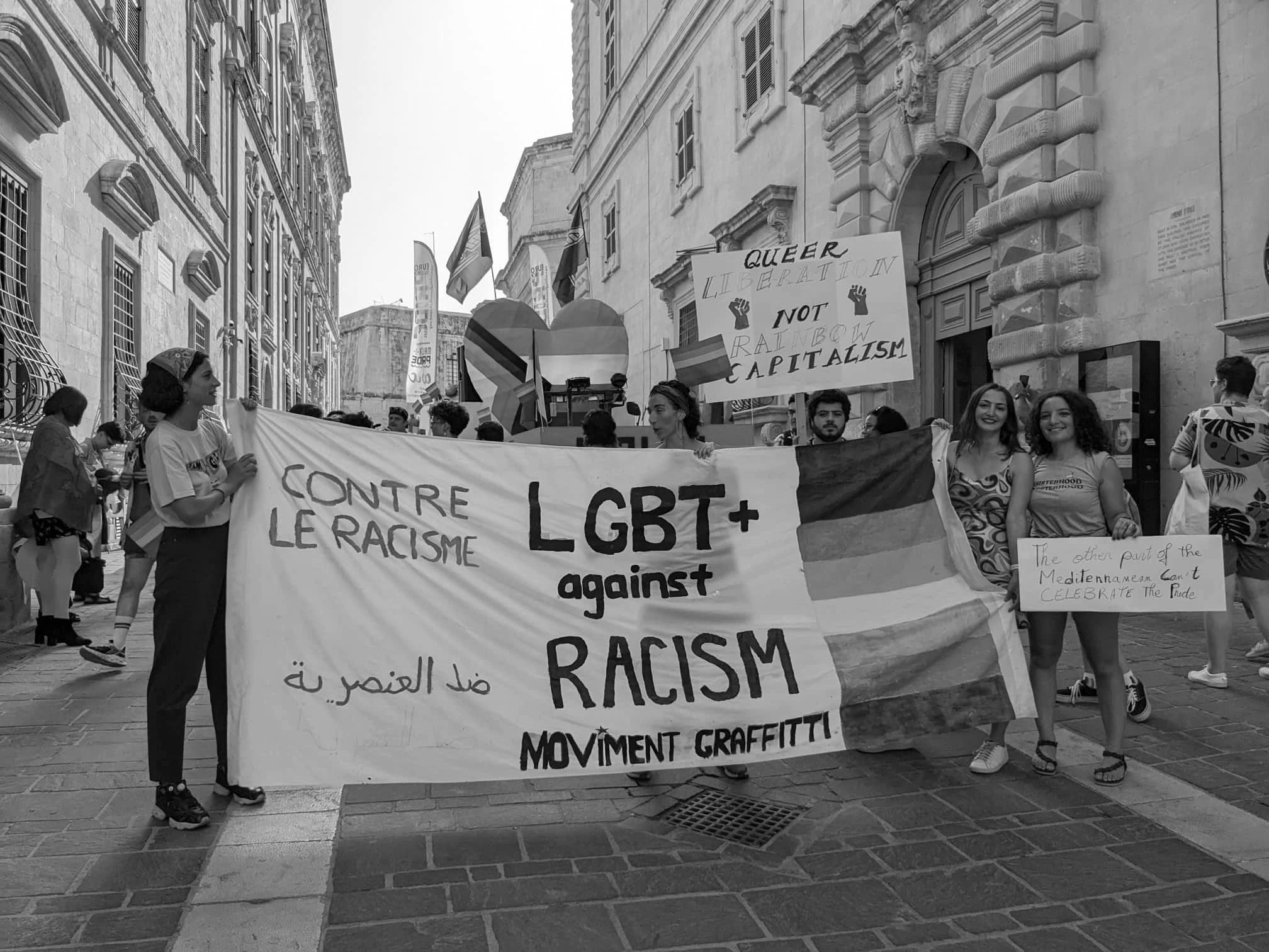 Several activists are holding up a banner advocating for LGBTQ- rights and anti-racism 