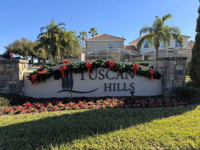 Tuscan Hills entrance sign decorated with holiday garland and red bows.
