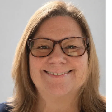 Smiling woman wearing glasses with light brown hair.