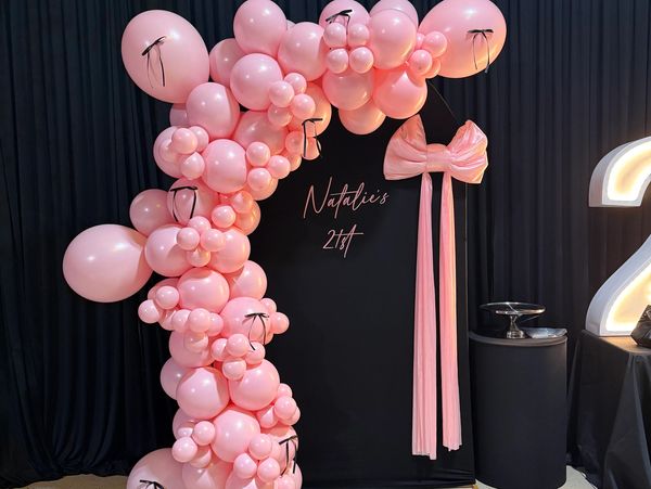 Pink balloon arch with black ribbons and a bow for Natalie's 21st birthday.