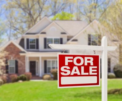 A house with a 'For Sale' sign in front.