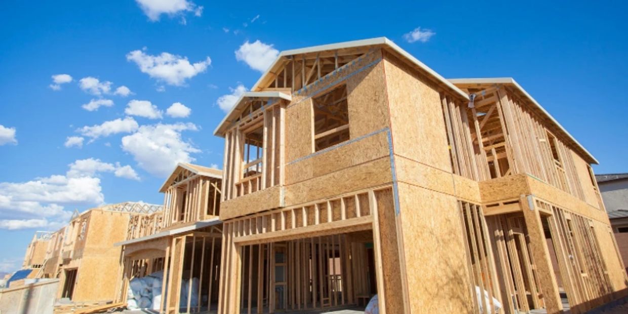 Wooden frame house under construction on a sunny day.