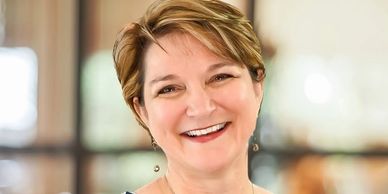 Smiling woman with short hair in a bright setting.