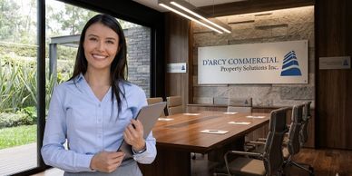 Smiling businesswoman holding a tablet in a modern conference room.