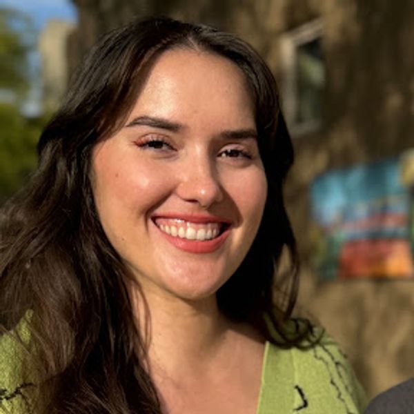 Smiling woman with long dark hair outdoors.