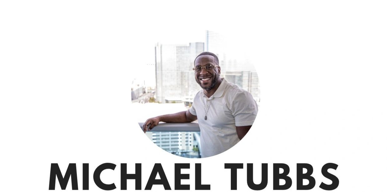 Smiling man named Michael Tubbs leaning on a balcony with city buildings behind him.