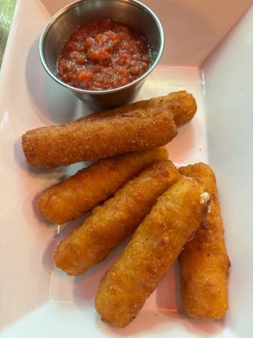 Plate of crispy mozzarella sticks with marinara sauce.