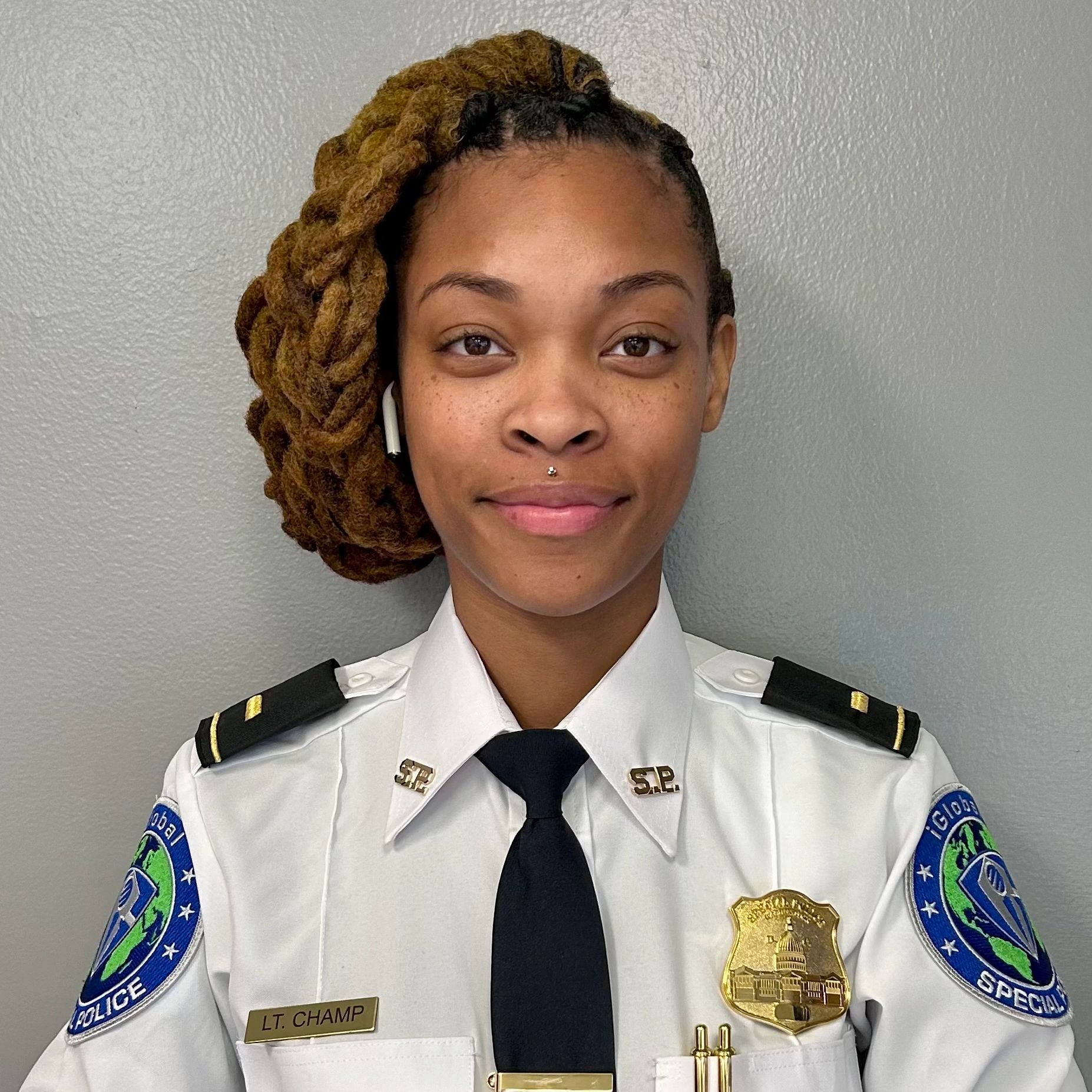 Smiling female police officer in uniform with braided hair.