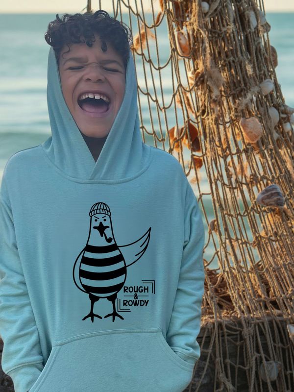 Boy in a blue hoodie laughing by the sea with a fishing net background.
