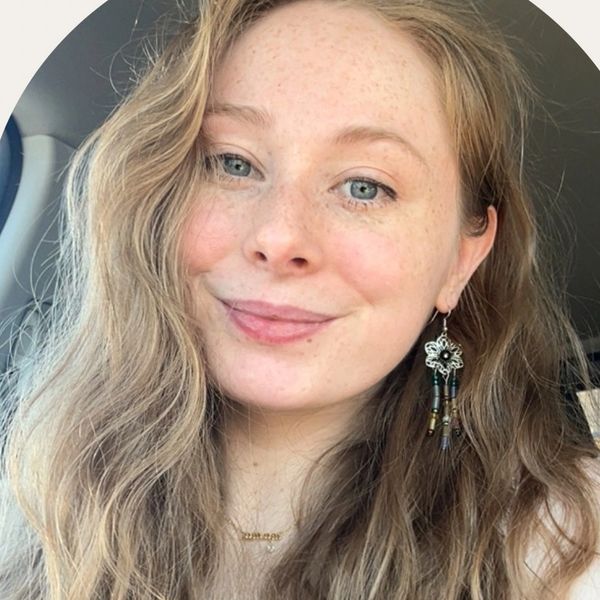 Young woman with wavy blonde hair smiling in a car.