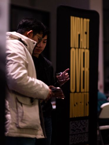 Two men standing near a sign that reads 'IMPACT OVER MOMENTS'.