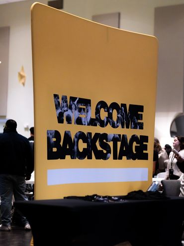 Large yellow sign saying 'WELCOME BACKSTAGE' at an event.