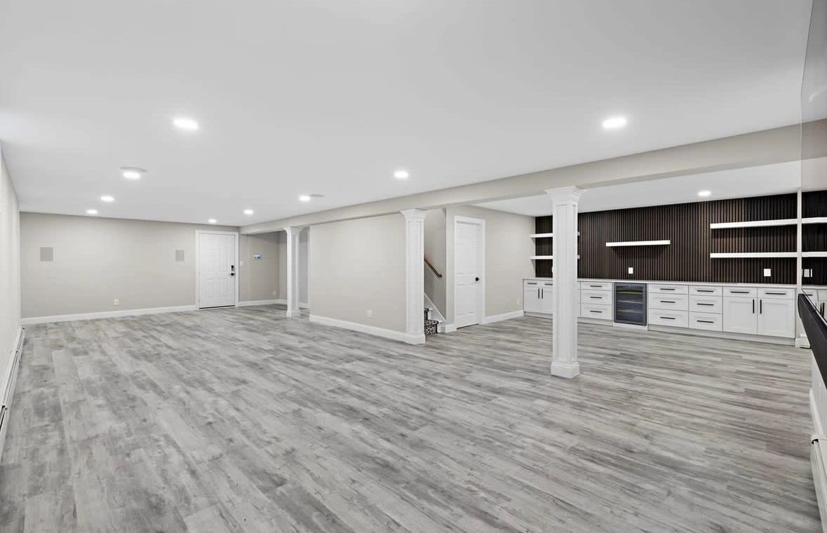 Finished basement remodeling project by Kingdom Empire LLC featuring custom cabinetry, new columns, new flooring and recessed lighting.