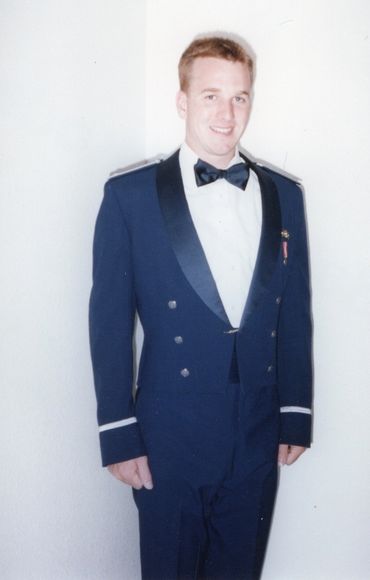 Man in formal military dress uniform smiling for a portrait.