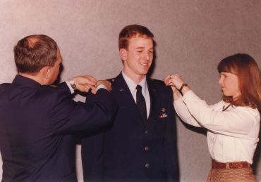 A young man in military uniform being pinned by two people.