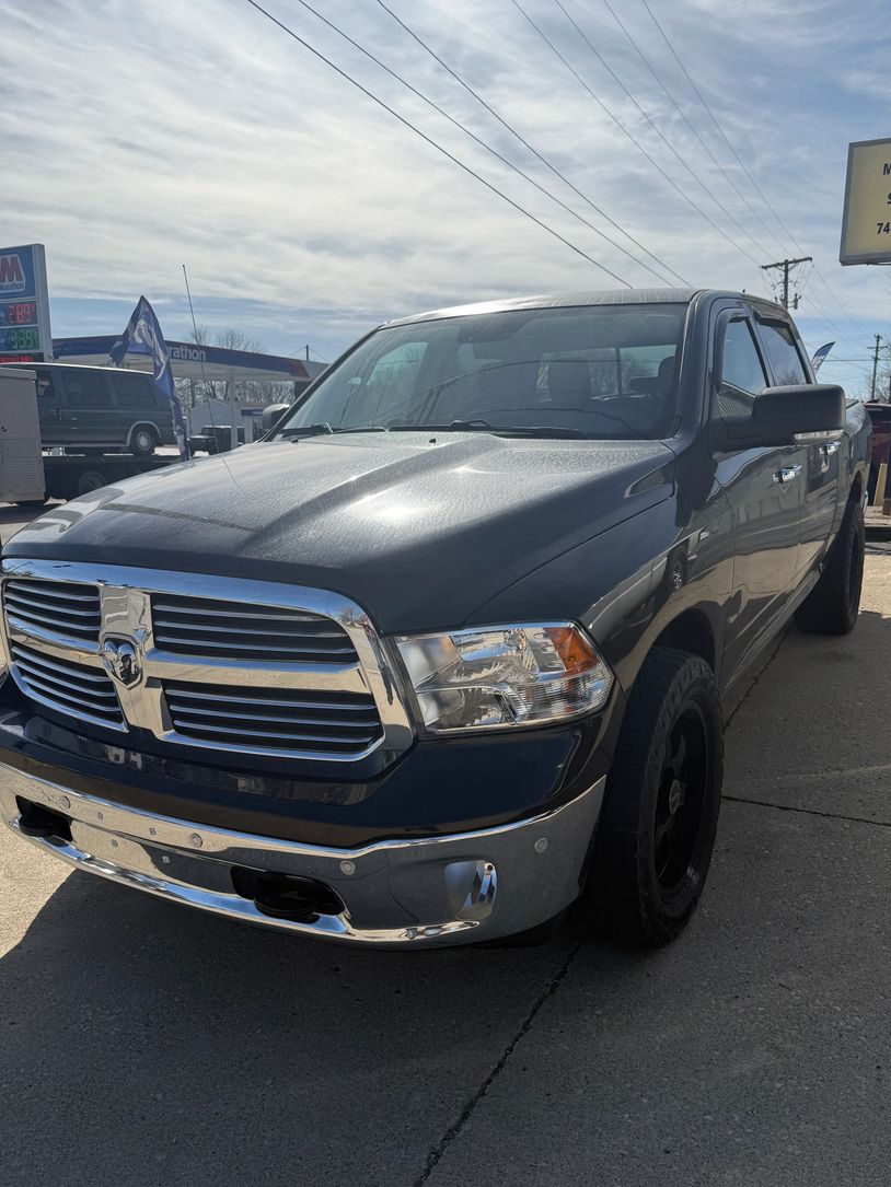 Black Dodge Ram pickup truck parked on concrete under a cloudy sky.