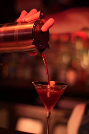 Pouring a cocktail into a martini glass.