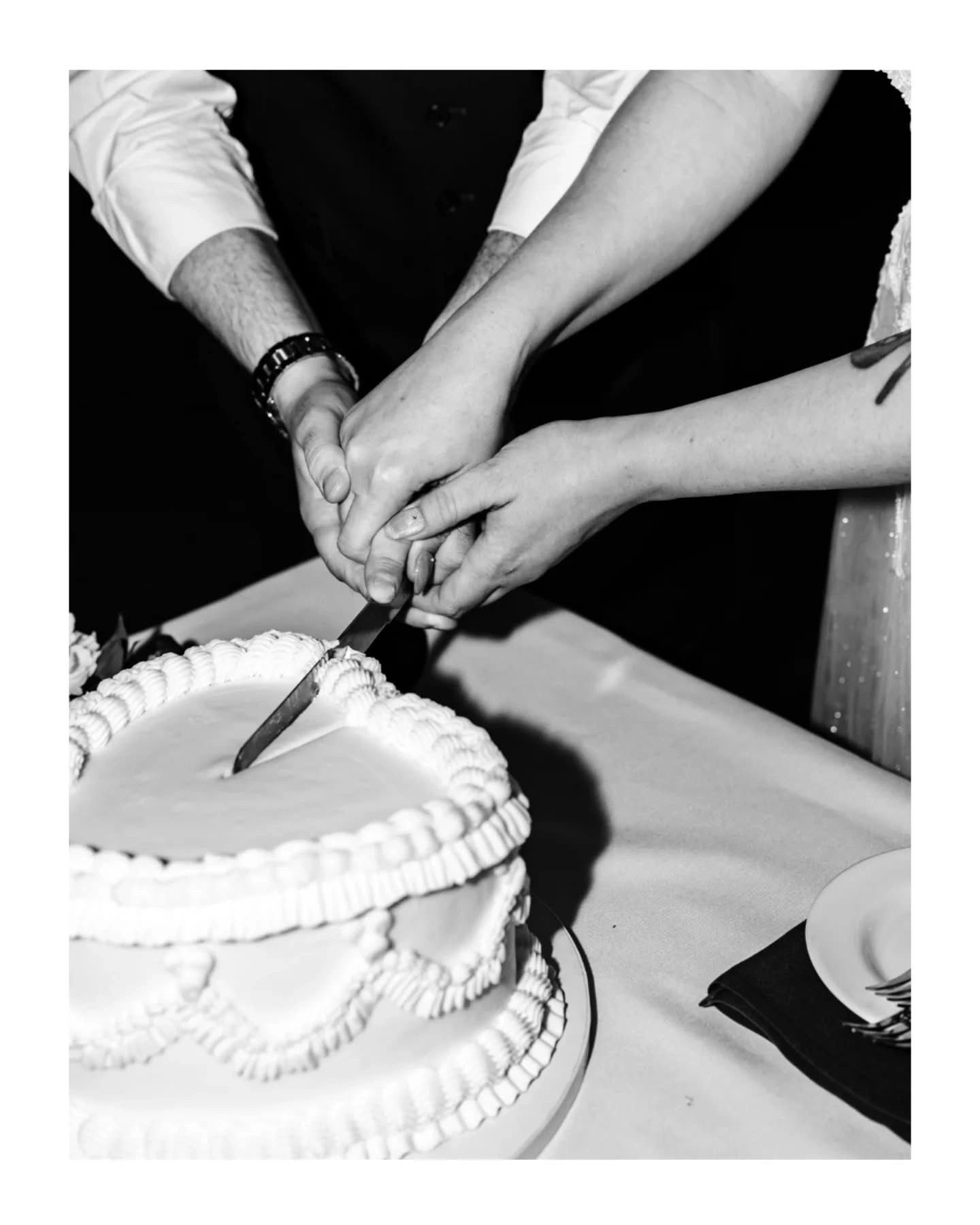 Black and white image of a wedding cake being cut