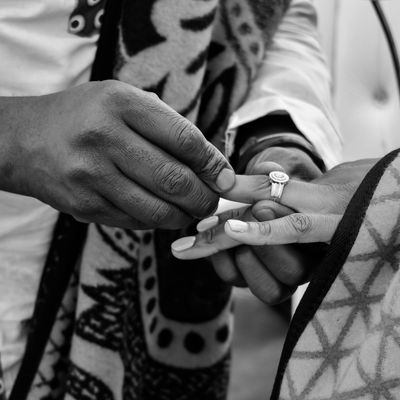 Close-up of a person placing a ring on another's finger during a ceremony.