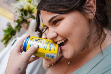 Woman laughing as she holds a yellow can near her mouth.