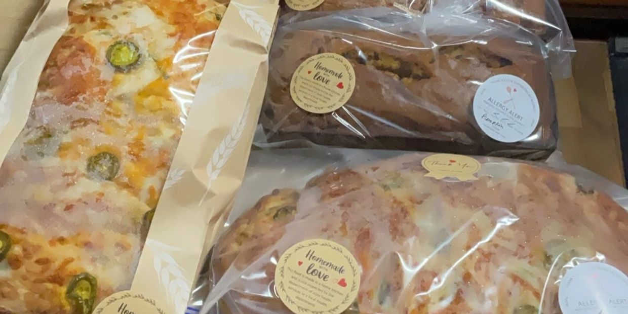 Assorted homemade baked goods wrapped in clear packaging with labels on a wooden table.