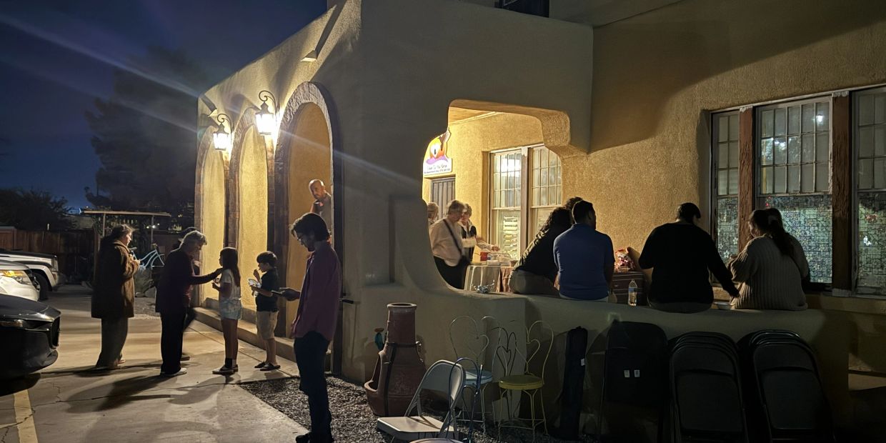 People gathered outside a lit building at night.
