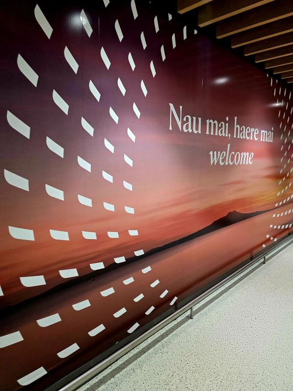 A mural with a sunset and the words 'Nau mai, haere mai welcome'.