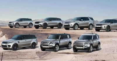 Seven Land Rover SUVs parked on a desert terrain under a clear sky.