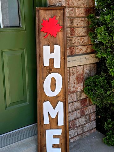 Wooden vertical sign saying HOME with a red maple leaf on top.