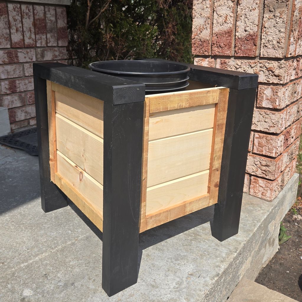 Handmade wooden planter box with black frame and natural wood panels.