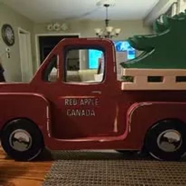 A red toy truck with a green tree in the back, labeled 'Red Apple Canada'.