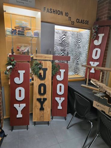 Wooden signs spelling 'JOY' with holiday decorations in a classroom corner.