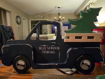 Decorative wooden truck with a Christmas tree on its bed.
